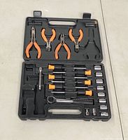 Opened black plastic carrying case displaying 20-piece tool kit including pliers, screwdrivers, ratchet wrench, socket wrench extensions, and sockets