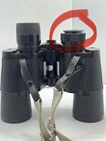 Close-up of the eyepiece and focus knob of black Bushnell binoculars with textured grip and straps.