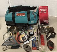 Image shows a Makita branded tool bag filled with assorted hand tools, power tool accessories, and an automotive air filter in a red box.