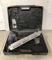 Full view of the Campbell Hausfeld pneumatic framing nailer inside its black, orange-accented plastic carrying case with compartments.