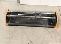 Top view of the HDX tile cutter showing metal rails and black base with orange ends.