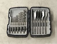 Open drill bit case showing left side with various metal twist drill bits and right side with flat wood-tone spade drill bits.