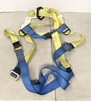 Full body safety harness laid flat showing all straps, buckles, and adjustment components; yellow and blue color scheme visible