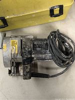 Motomax 4.5 inch tile cutter power tool with coiled power cord and black handle, showing signs of use and dirt.