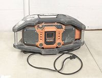 Photo showing front and top view of Ridgid construction radio with attached power cord.
