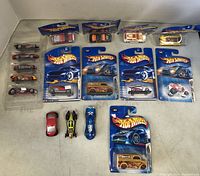Top-down view showing all Hot Wheels cars in package and loose, arranged on a flat white surface.