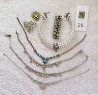 All eight pieces of rhinestone jewelry arranged on white fabric showing necklaces, pins, and bracelet