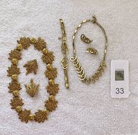 Sara Coventry and Dauplaise sets displayed on white cloth, showing two necklaces, bracelet, earrings, and brooches
