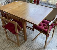Wooden dining table set with four chairs, showing the table fully extended with two chairs visible.