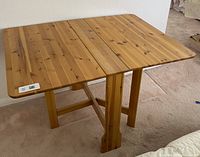 Front and side view of the table set up showing the wooden plank surface, legs, and foldable design.