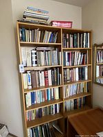Full bookshelf showing various books organized on wooden shelves, some stacked on top.