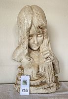 Front view of beige painted metal bust of a woman with cello, showing facial expression and body posture with some paint discoloration.