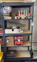 Photo of a gray metal shelving unit with particle board shelves showing five levels. Various items are on the shelves but are not included in lot.