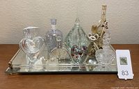 Full arrangement showing mirrored vanity tray with eight perfume bottles of differing sizes and shapes, including heart-shaped and decorated bottles.