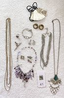 Wide photo showing the entire lot of jewelry items laid out on a towel, including earrings, necklaces, bracelet, and rings.