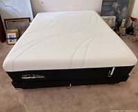 Full view of white-topped mattress on black foundation in room