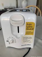 Front view of white Proctor Silex toaster showing control knob, lever, and safety labels.