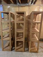 Photo showing three wooden shelving units side-by-side in a basement with exposed insulation.