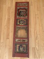 Full length view of carved wood window frame with multiple inset hand carved panels showing figures and decorative motifs.