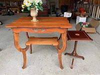 Game table and stand photographed together in a storage environment, showing the entire pieces and wood finish.
