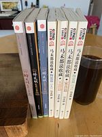 Spine view of 8 Chinese books including titles related to antique collecting by Ma Weidu; some books have white covers with image of vase, others black and brown covers.