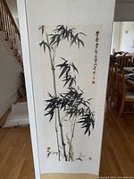 Full view of the vertical hanging Chinese scroll displayed in a room, showing bamboo painting and calligraphy.