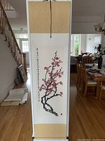Full view of the Chinese scroll hanging, showing the plum blossom art and the gold silk borders.