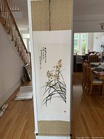 Full view of Chinese scroll painting hung vertically, showing orchid artwork and calligraphy.