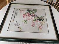 Framed Chinese watercolor painting featuring pink orchids and two butterflies with Chinese calligraphy on the left side.