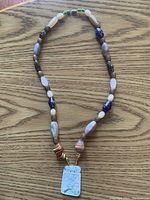 Full view of necklace displaying variety of semi-gemstone beads on a wooden surface