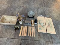 Overview of all items arranged on a tiled floor showing the flower pot, wooden panels, carved sticks, ink bottle, brush, small decorative tree, and stone ink slab.