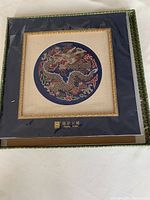 Framed brocade panel with overall view of dragon embroidery, blue and beige matting with decorative gold trim