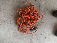 Coiled long orange extension cable on concrete floor.