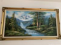 Full view of framed oil painting showing forest, river, waterfalls, mountains, and sky