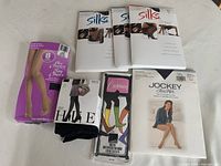 Front view of all pantyhose and socks packaging arranged on a table, showing Silks, Jockey, Hue, and Carmen brands.