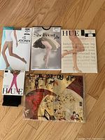 Lot includes 4 pairs of new silk sheer stockings in original packaging and 1 silk scarf with Asian design on wooden floor.