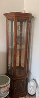 Solid wood corner china display cabinet with glass shelves and wooden lower storage compartment in corner setting.