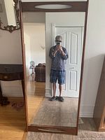 Front view of tall rectangular floor mirror with solid wood frame and clear reflective surface.