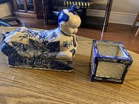 Porcelain boy figurine resting on rectangular base showing exterior detail and colors