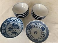 Top view of small and medium blue and white Japanese rice bowls stacked separately with two bowls displayed in front showing interior floral and geometric blue patterns on white ceramic.
