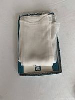 White silk scarf folded inside a decorative box, showing texture and size