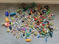 Overview photo showing a large assortment of toy animals and accessories spread on the floor