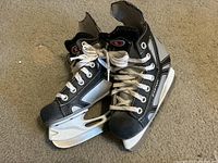 Pair of Easton hockey skates with black, gray, and white details, worn condition on beige carpet.