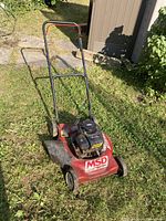 Full view of red MSD lawnmower with Briggs and Stratton motor, placed on grass showing overall condition and size.