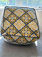 Front view of ottoman/floor pillow showing yellow and gray floral geometric patterned fabric