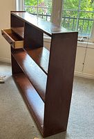 Side angled view showing the wooden shelf unit's double-sided access and drawer partially open.