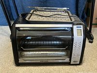 Front view of Black and Decker toaster oven including the glass door, interior rack and baking tray on top.