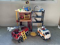 Overall view of Fisher Price fire station set with fire truck, ambulance, firefighting plane, figures, and building.
