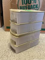 Four stacked beige plastic Tupperware storage containers with matching lids, secured with clear tape.