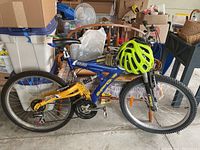 Side view of blue Hooligan SuperCycle mountain bike with 26-inch wheels placed in a garage setting alongside other stored items.